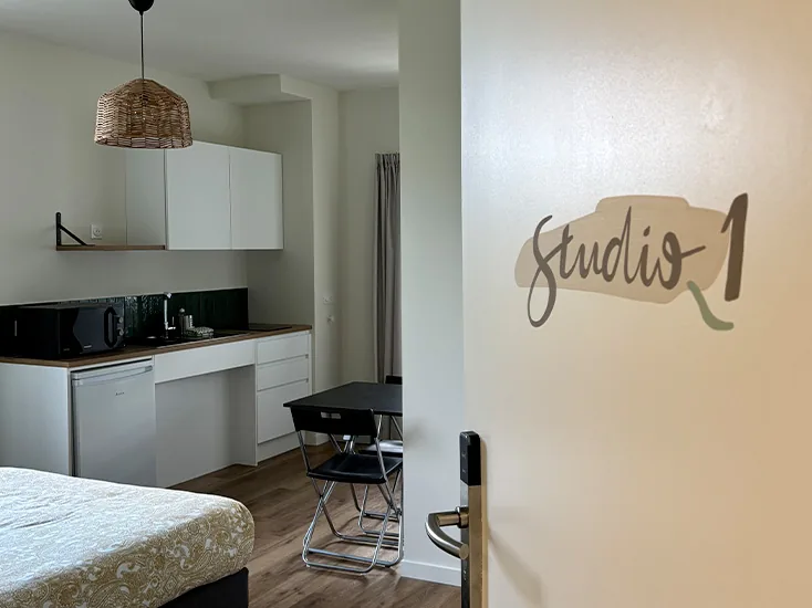 coliving-studio-1-vue-ensemble-le-chateau-bayonne Studio 1 en vue d'ensemble : cuisine, îlot avec tabourets et lit