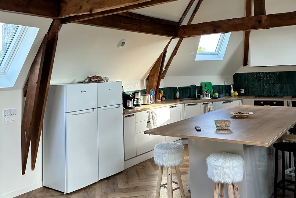 Cuisine commune sous combles avec îlot central et tabourets