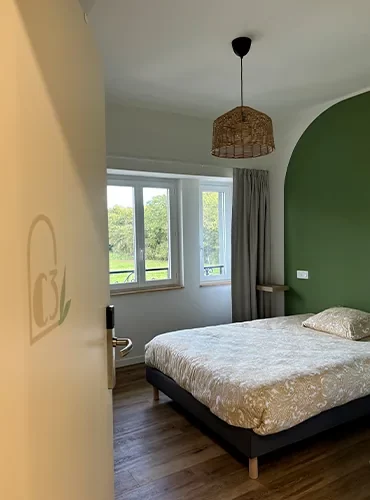 Chambre double aux murs ocre et vert, fenêtres donnant sur le parc
