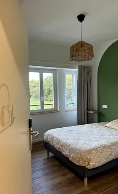 Chambre double aux murs ocre et vert, fenêtres donnant sur le parc
