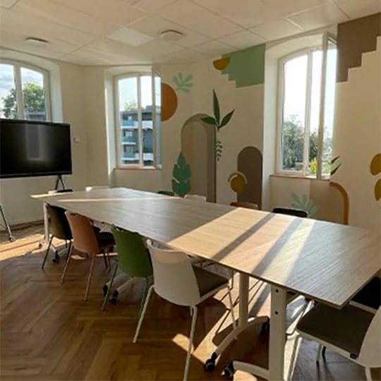 Salle de réunion avec longue table, écran mural et fresque végétale